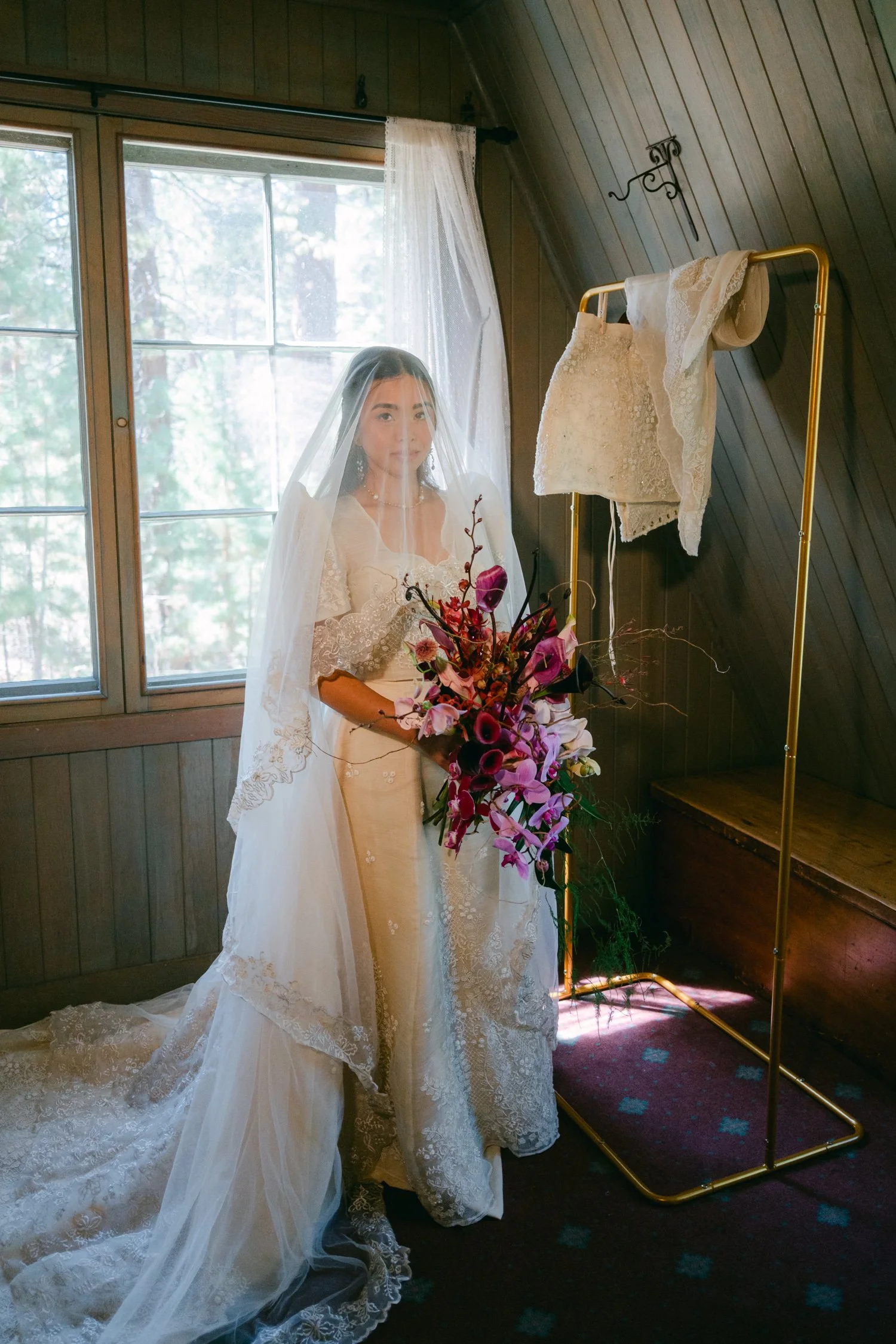 A Valhalla Lake Tahoe Wedding, photo of the bride wearing a vintage-style lace veil and holding a vibrant bouquet of dark pink and purple flowers