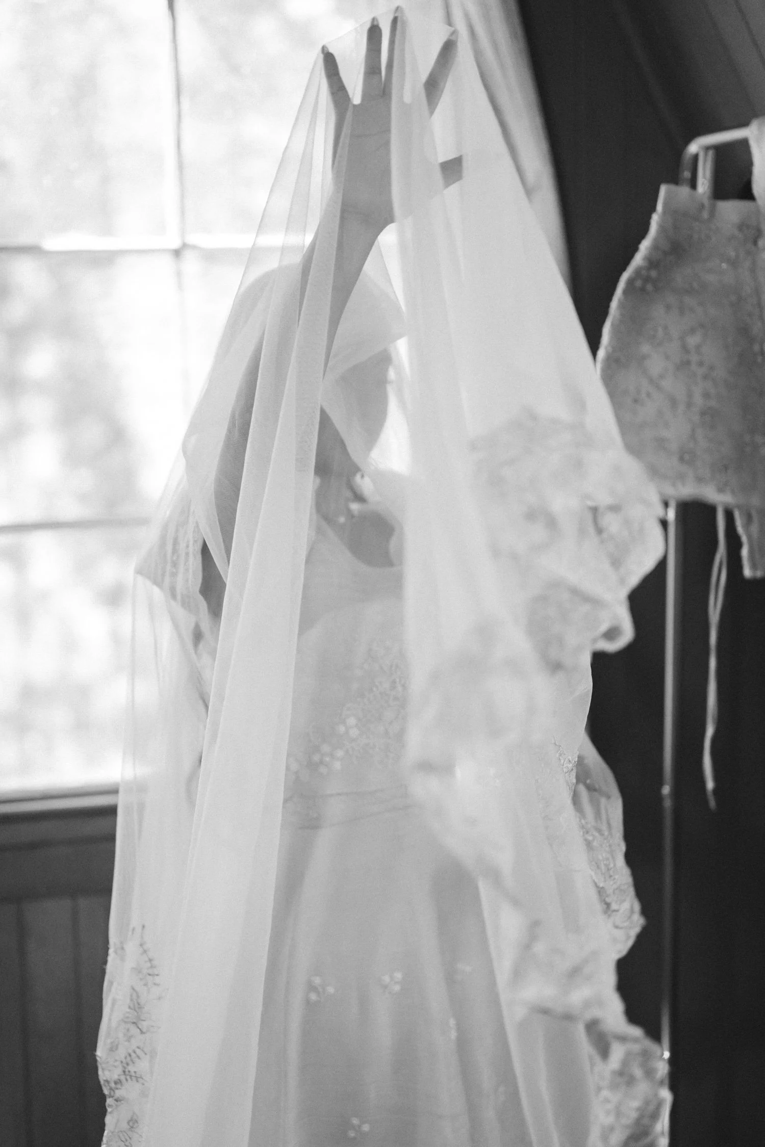 A Valhalla Lake Tahoe Wedding, photo of the bride holding a delicate white tulle veil over her face in a softly lit room.