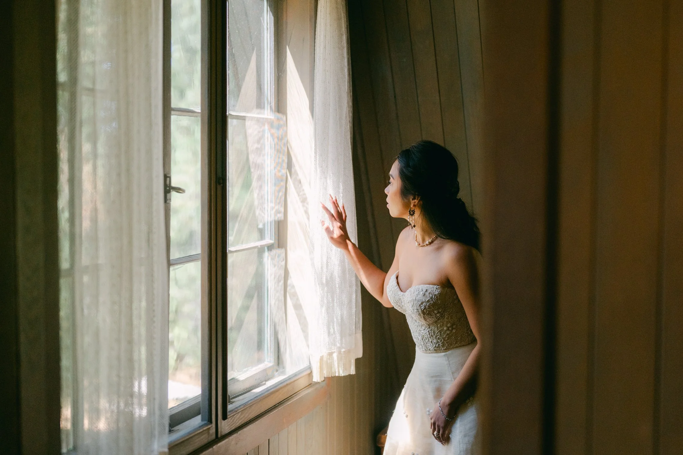 A Valhalla Lake Tahoe Wedding, photo of the bride in a strapless sweetheart neckline bodice with intricate beading paired with a smooth skirt standing near a window