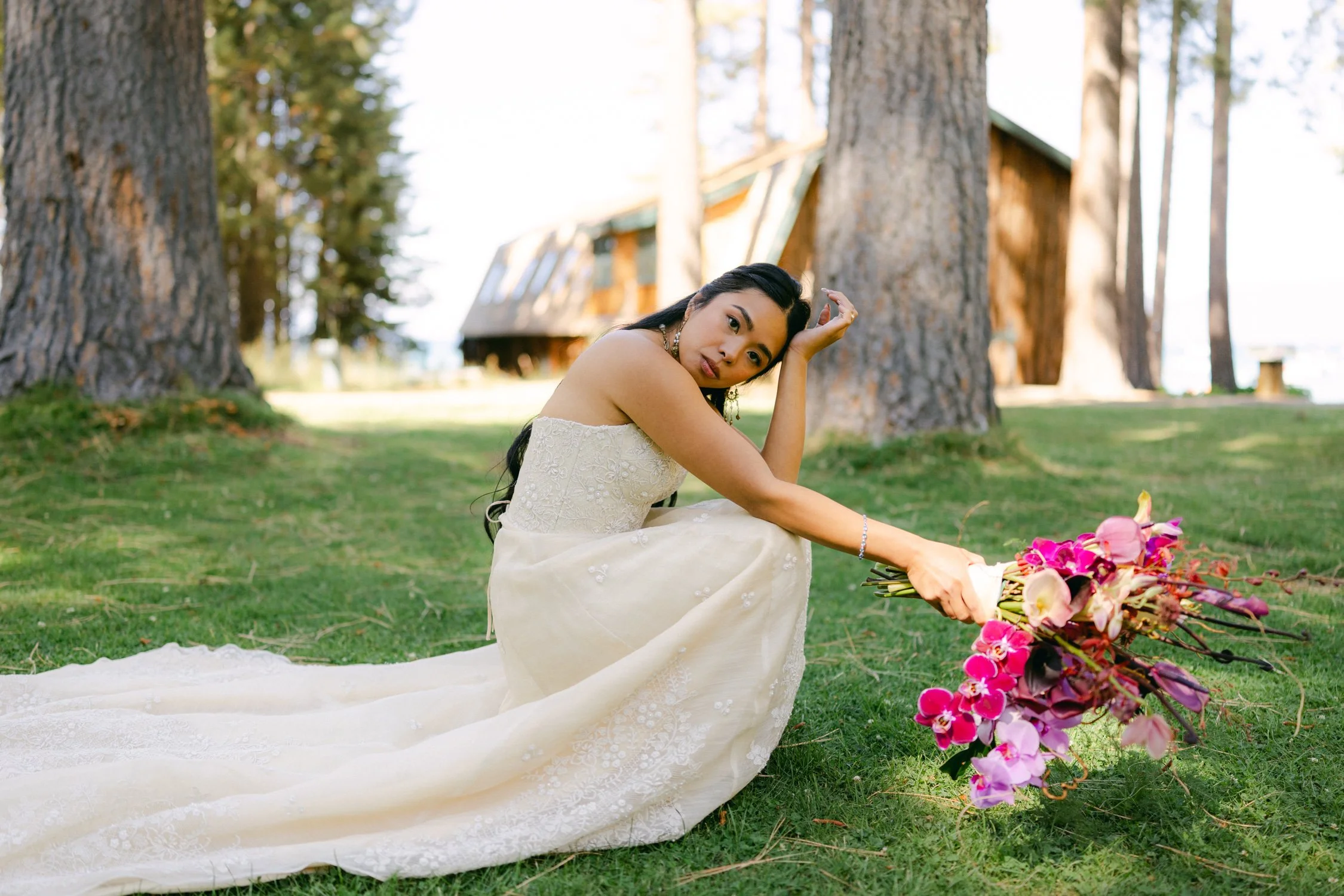 A Valhalla Lake Tahoe Wedding, photo of the bride in an ivory strapless gown with delicate floral embroidery holding a vibrant tropical bouquet.