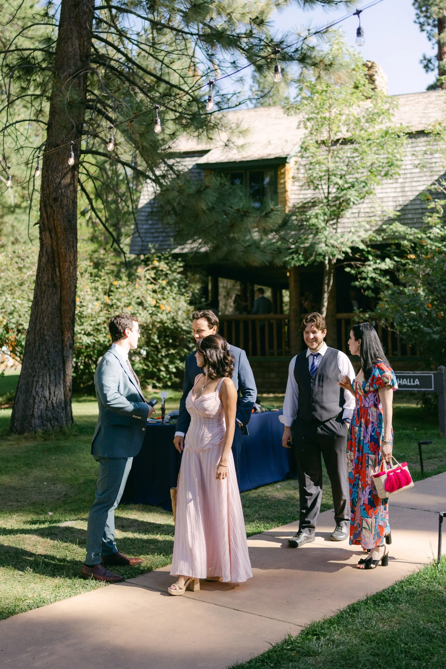 A Valhalla Lake Tahoe Wedding, photo of guests mingling outside a rustic wooden building during an outdoor wedding celebration