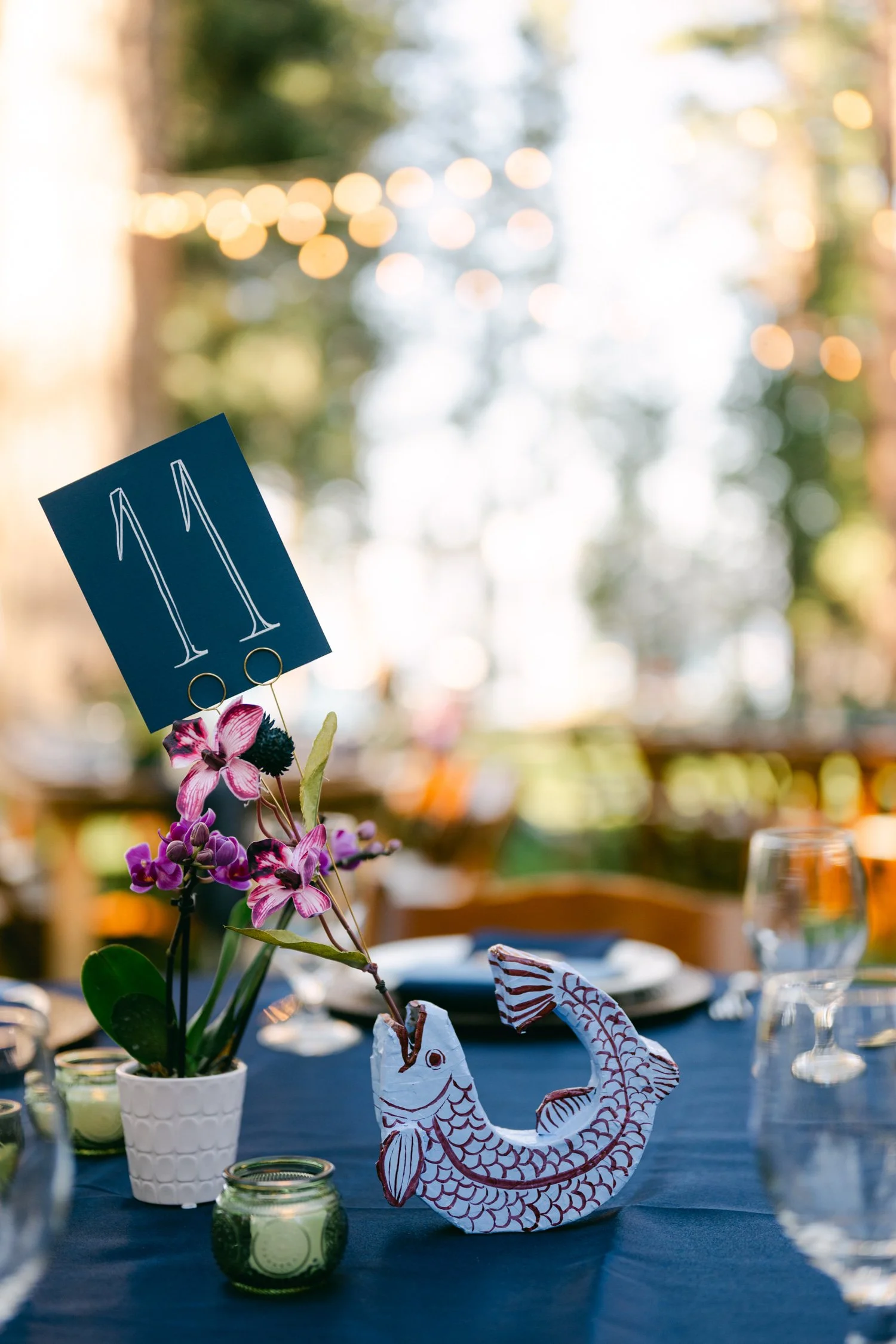 A Valhalla Lake Tahoe Wedding, photo of table number holder carved wooden fish adds a whimsical, artisanal touch to the tablescape.