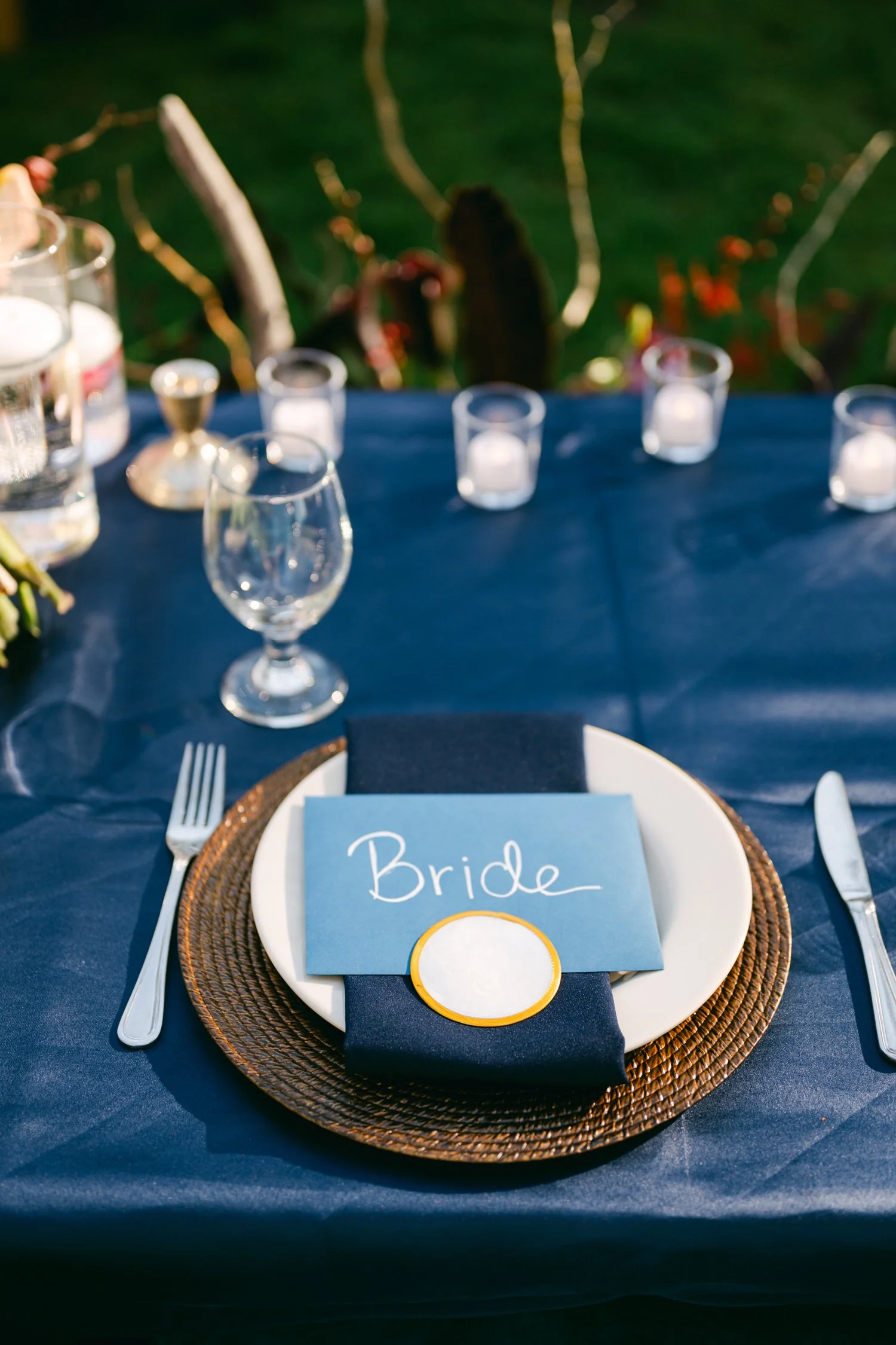 A Valhalla Lake Tahoe Wedding, photo of elegant table setting with a navy blue napkin and a place card label resting on a white plate over a woven charger
