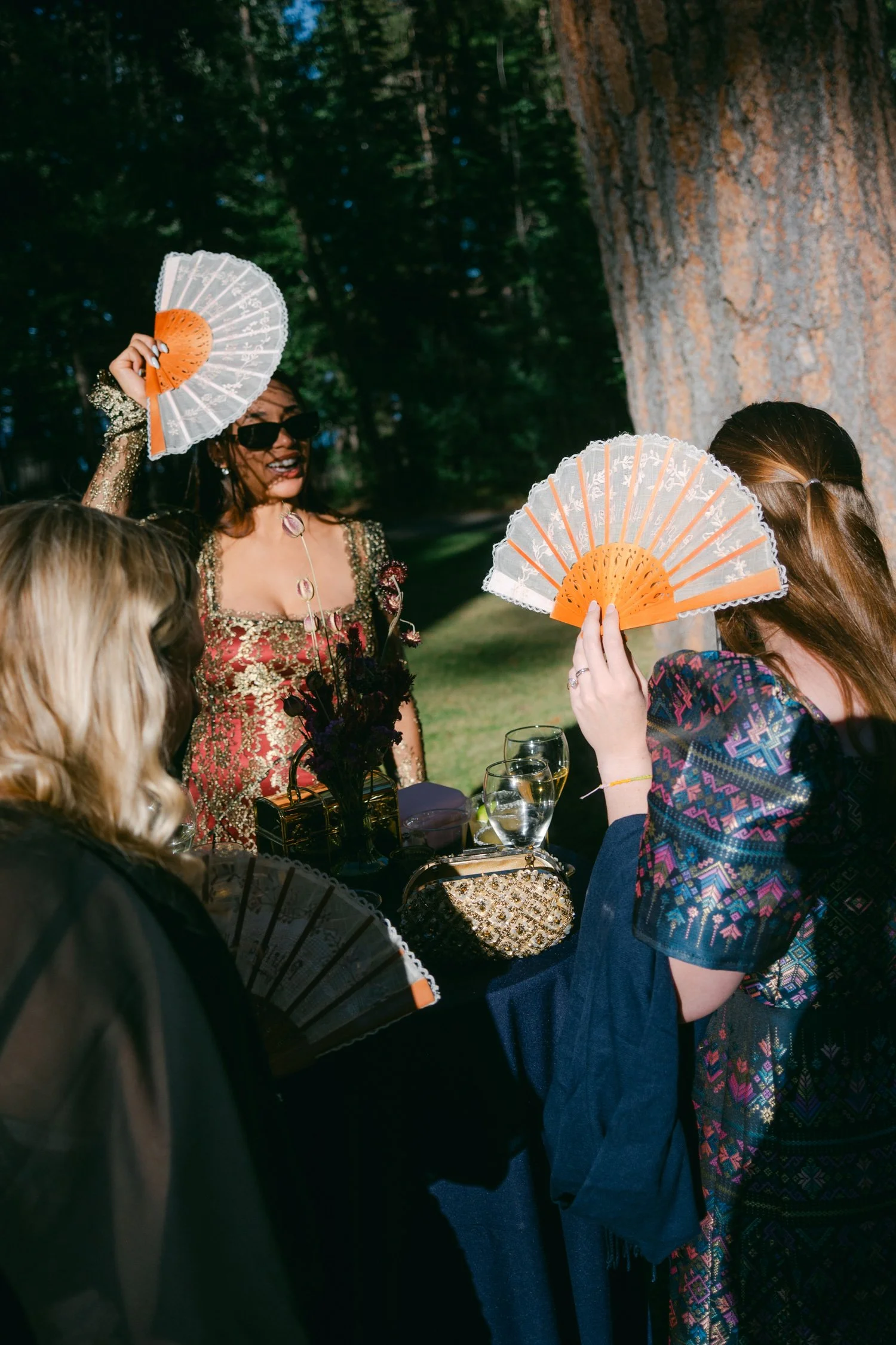 A Valhalla Lake Tahoe Wedding, photo of wedding guests dressed in traditional-style attire holding decorative hand fans outdoors