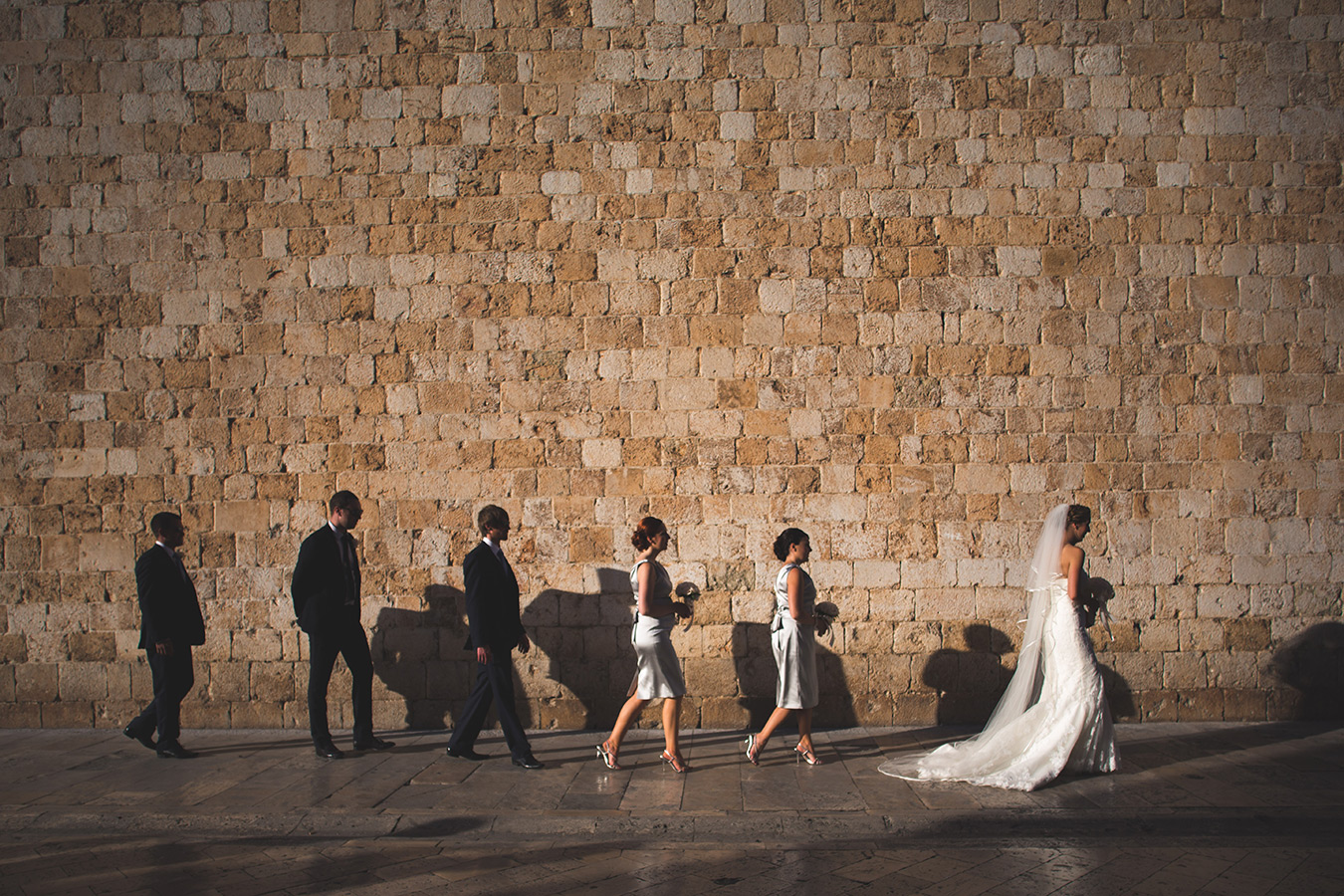 One of a set of images taken at this chic destination Wedding of Jenna & Nick. The stylish old town of Dubrovnik, Croatia.  The Bride and Bridesmaids walk down the street. Photography by Matt Porteous