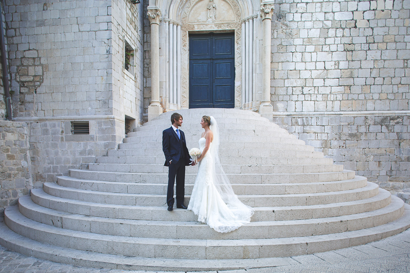 One of a set of images taken at this chic destination Wedding of Jenna & Nick. The stylish old town of Dubrovnik, Croatia.  The couple pose on the steps.  Photography by Matt Porteous