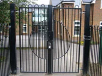 Black security fence and gate in front of a school playground.