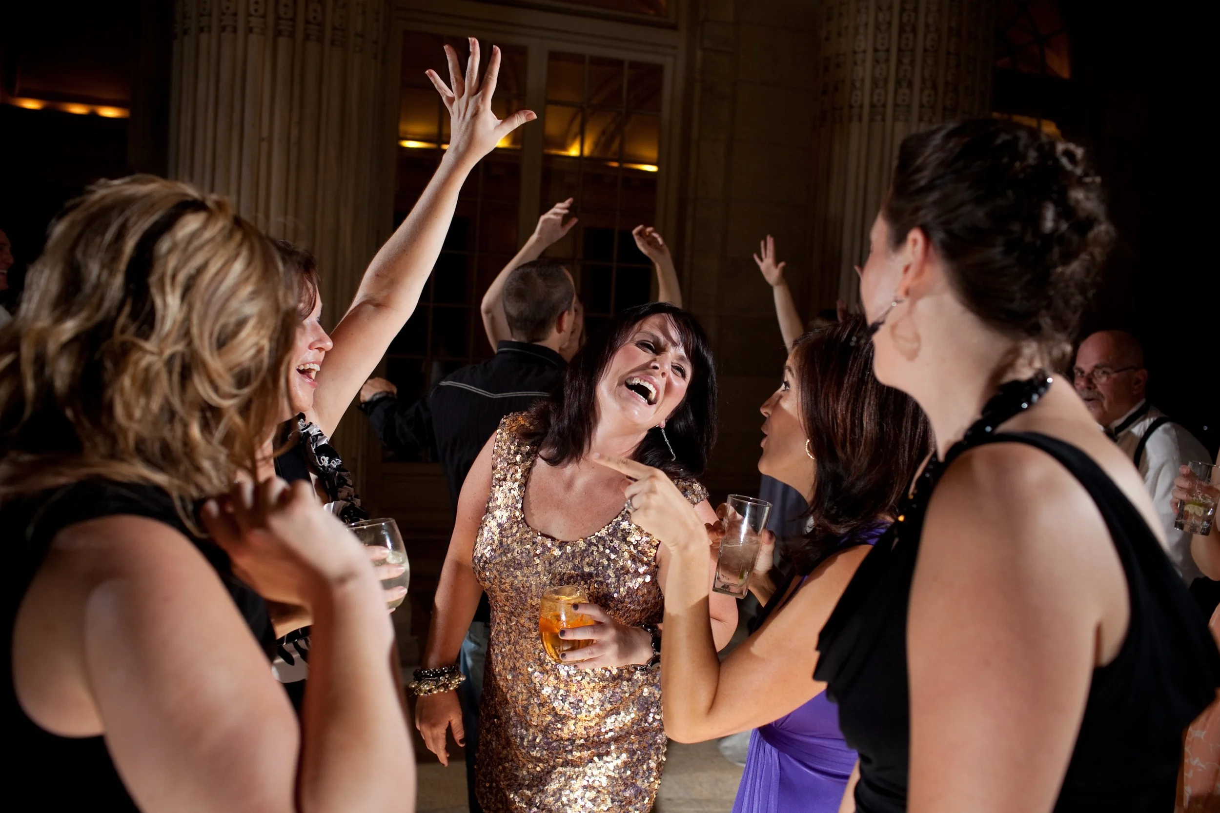 Group of women celebrating, drinking cocktails, and dancing at a social event or party.