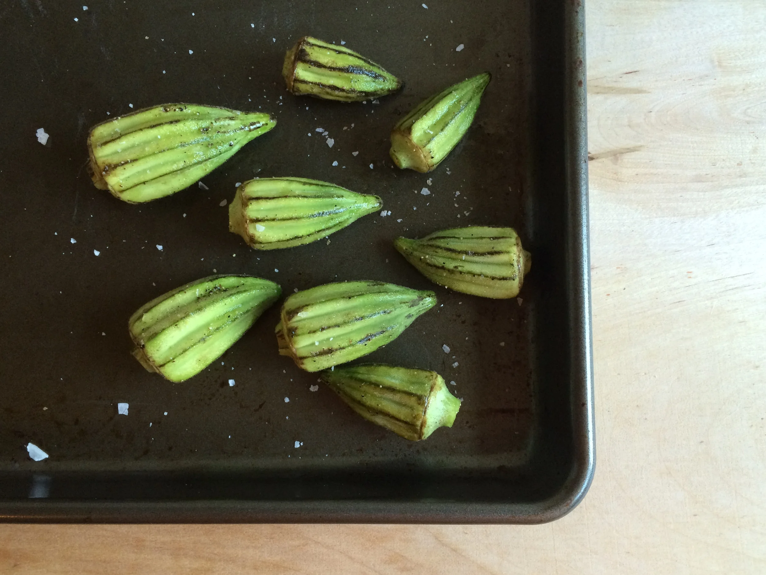 Place whole okra pods in a bowl and toss with olive oil, salt, and pepper.