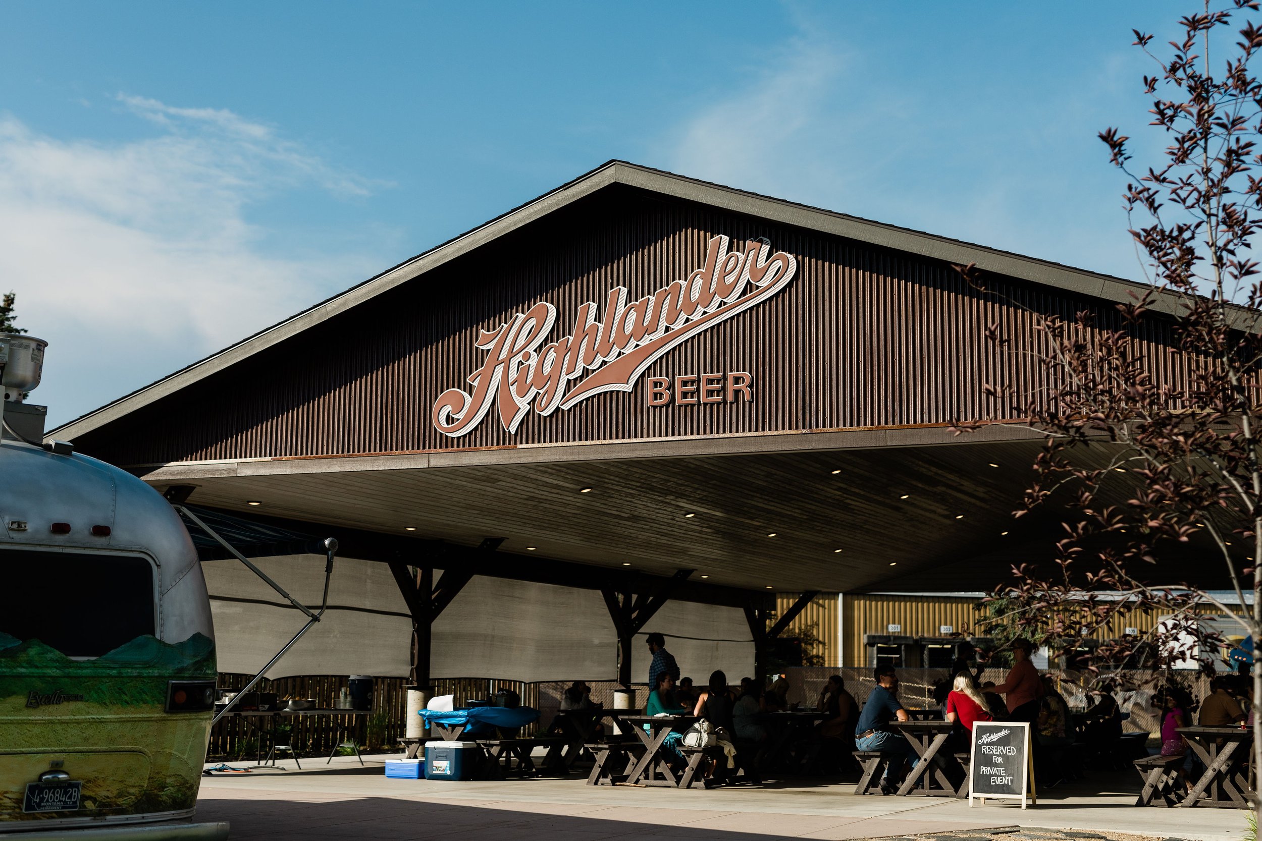  The outside of the pavilion in center with brown siding and big red logo and a blue sky 