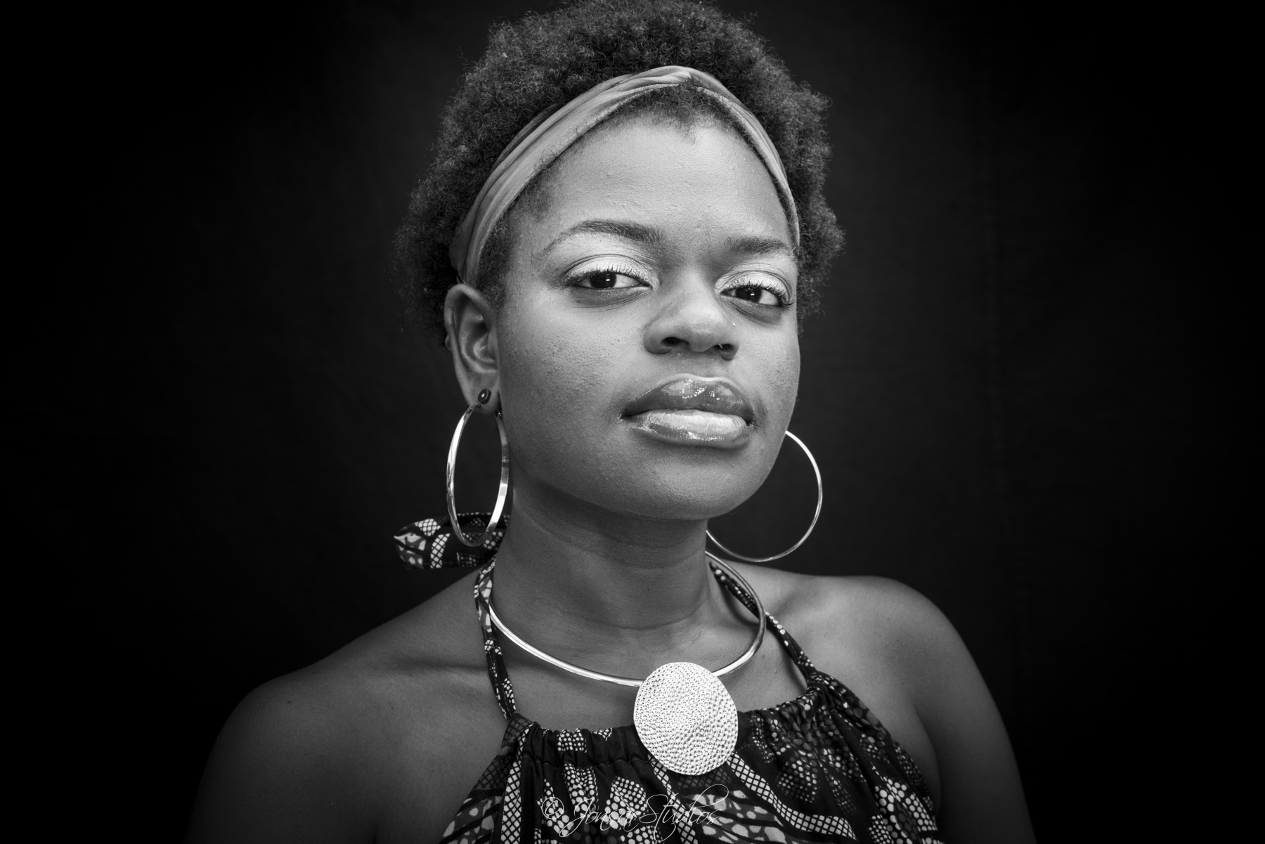 Proud African American Woman with hoop earrings, photographed on black background