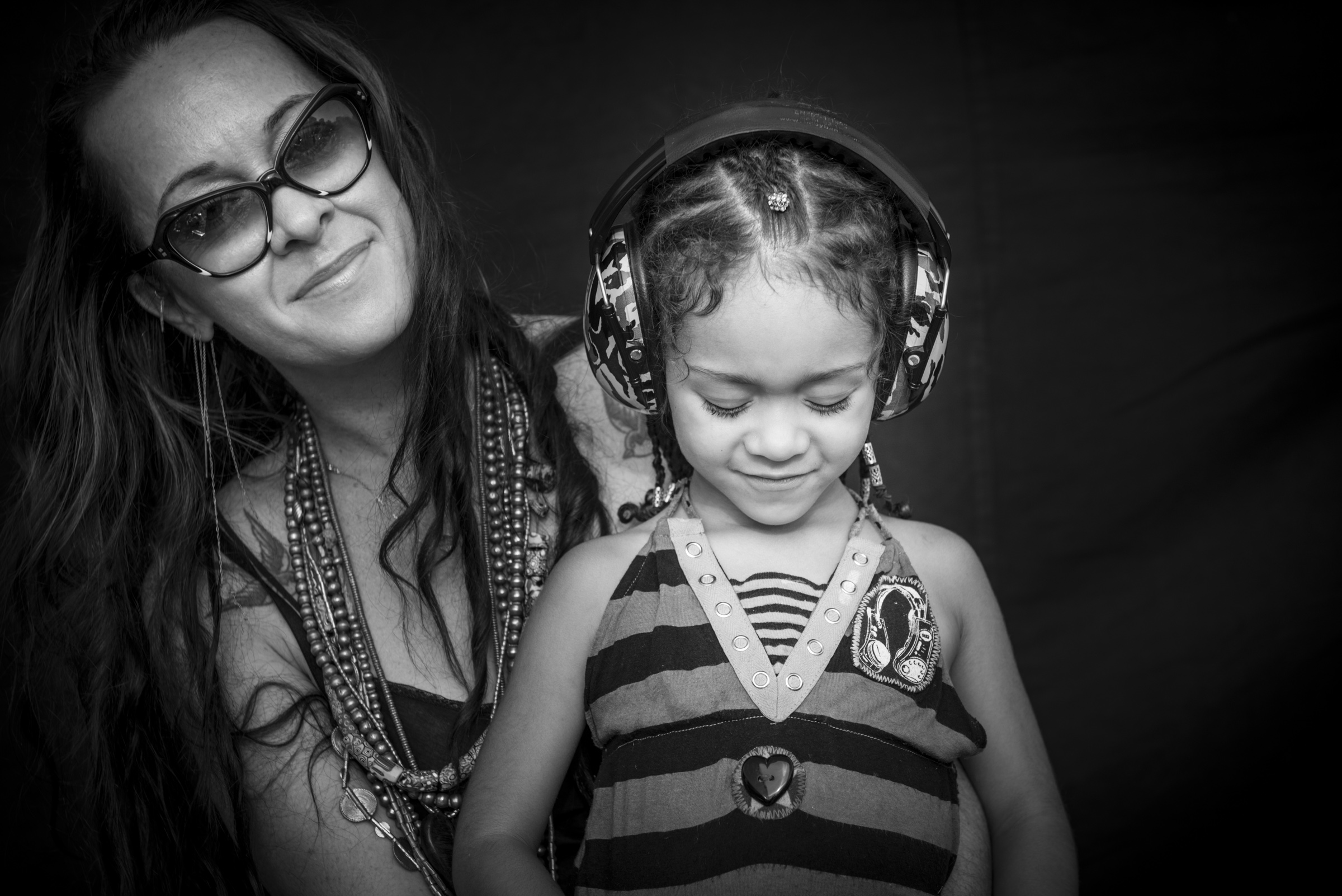 Mother with daughter in headphones photographed on black background