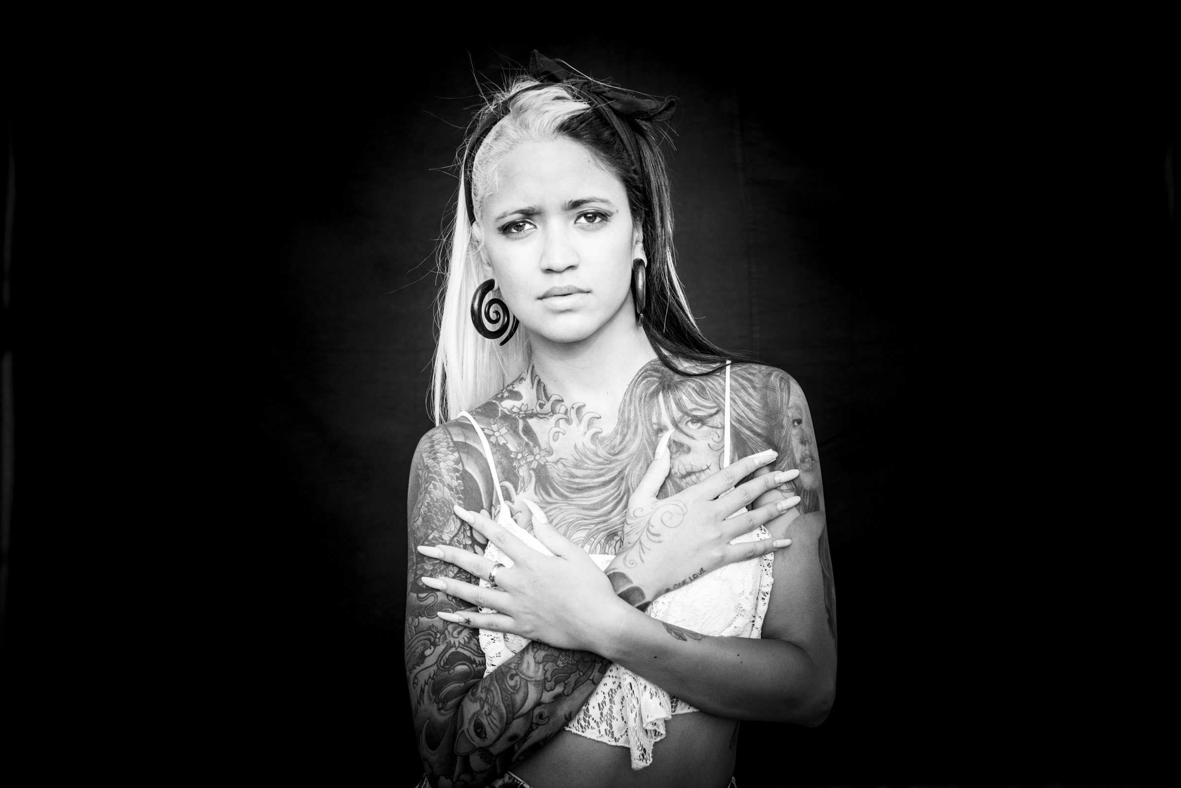 Woman with long nails and tattoos photographed on black background