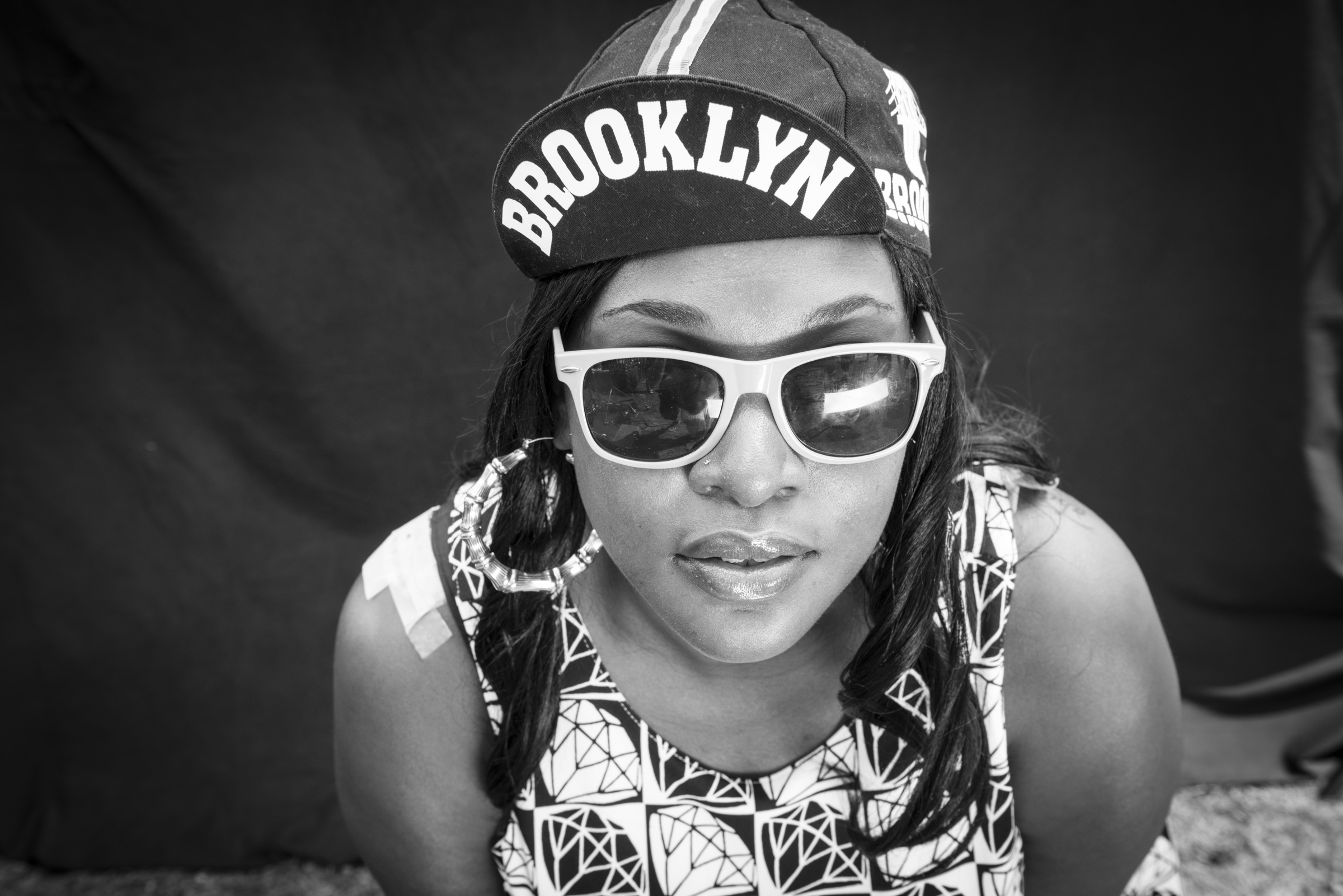 Portrait of woman wearing Brooklyn hat photographed on black background