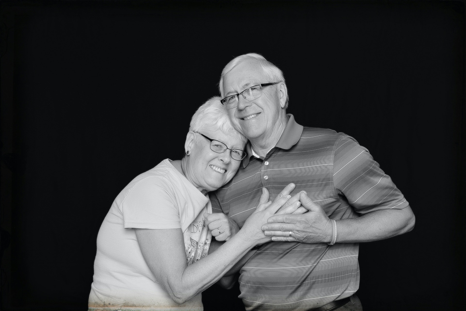 Husband and wife, caregiver and patient photographed on black background