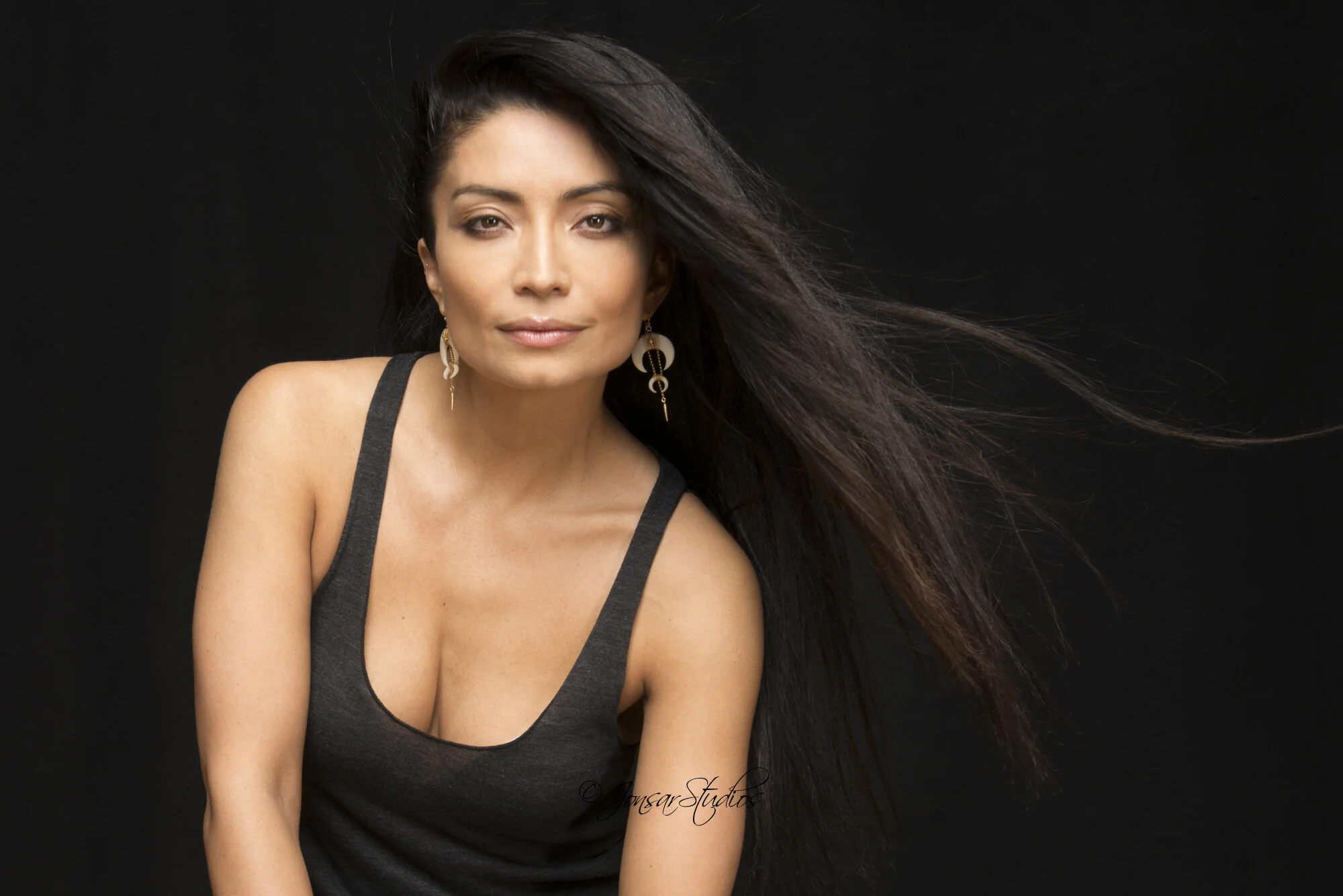 Color portrait of woman with long black hair on black background
