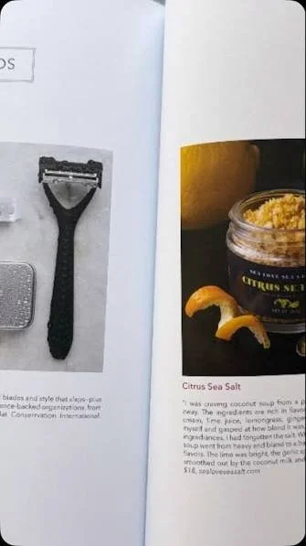 A picture of a razor on a page in a magazine or book, next to a jar of citrus sea salt and lemon peel.