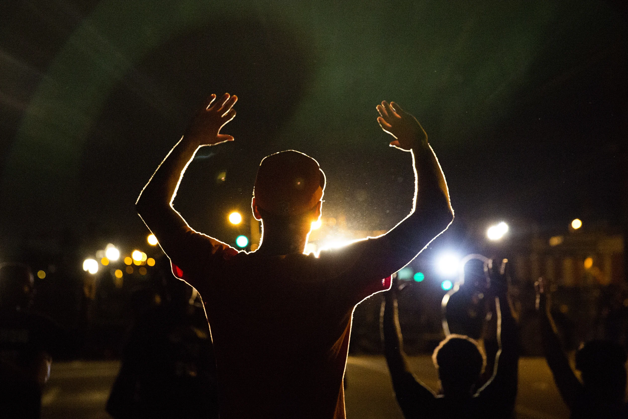  Demonstrators hold up their hands outside the burned and looted Quik Trip gas station Tuesday August 13, 2014 in Ferguson, Missouri. 