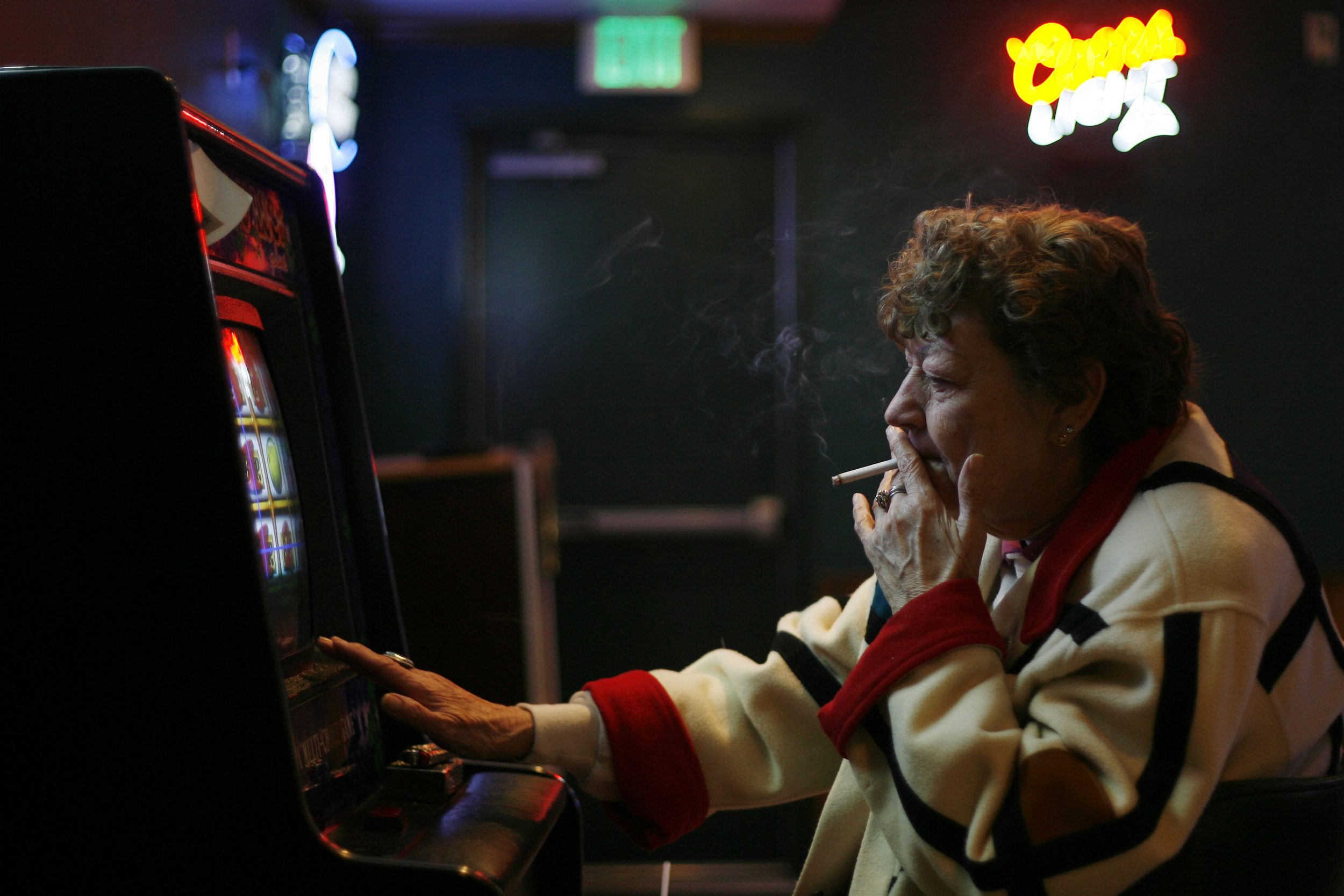 A woman smokes a cigarette at while using a video gambling machine at the Cheers bar in Chilton, Wisconsin.