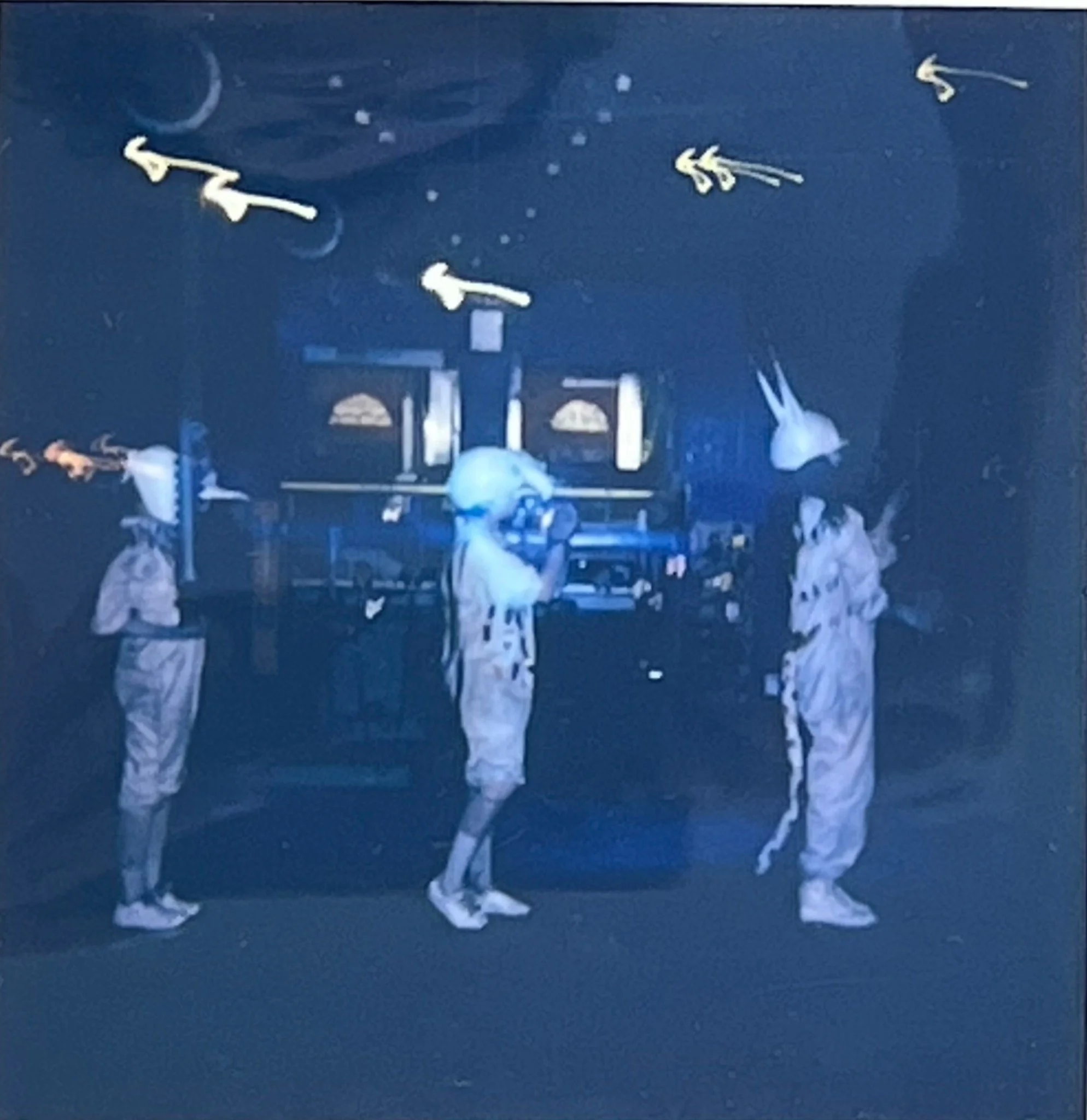 Three animal-like performers stand before a decommissioned machine beneath suspended white forms in The Paper Factory.