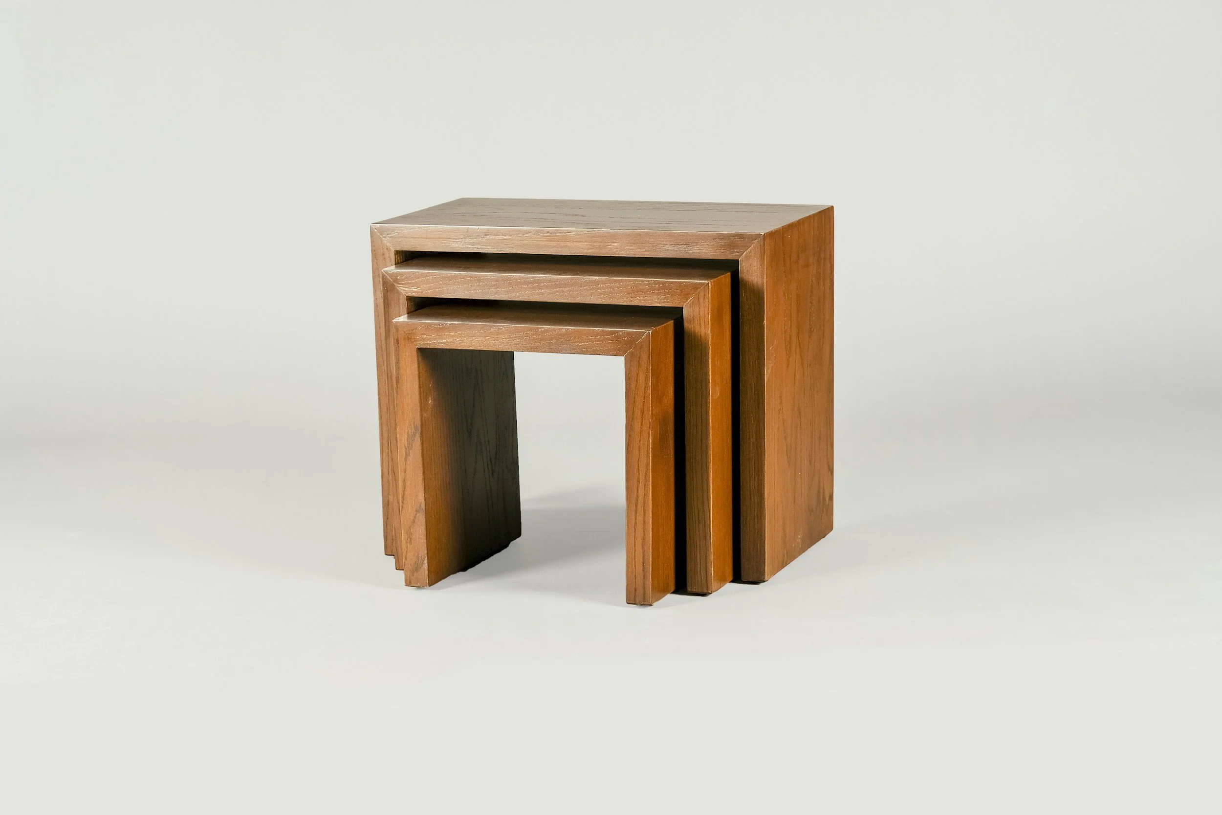 Drei ineinander gestellte Beistelltische aus warmem Holz vor hellem Hintergrund – Beispiel für reduzierte, nachhaltige Möbeldesigns im Interior