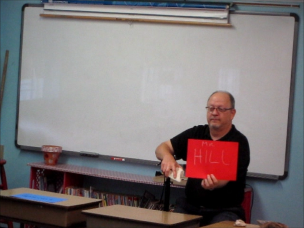 SGS Member Kevin Hill shows 3rd graders how a sedimentary rock with a fossilized oyster can write like sidewalk chalk.