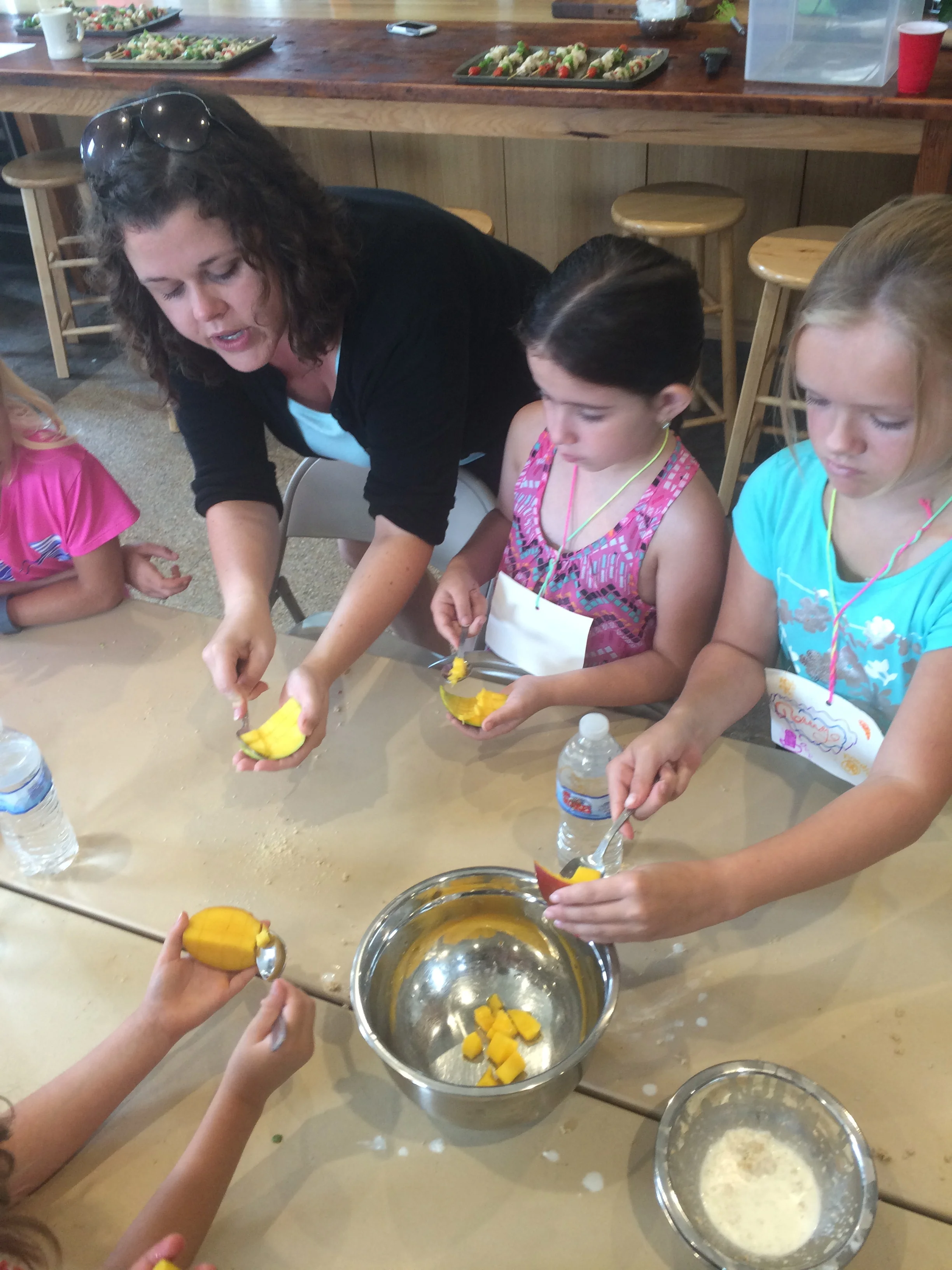 Miss Jennie demonstrating how to scoop out the mango.