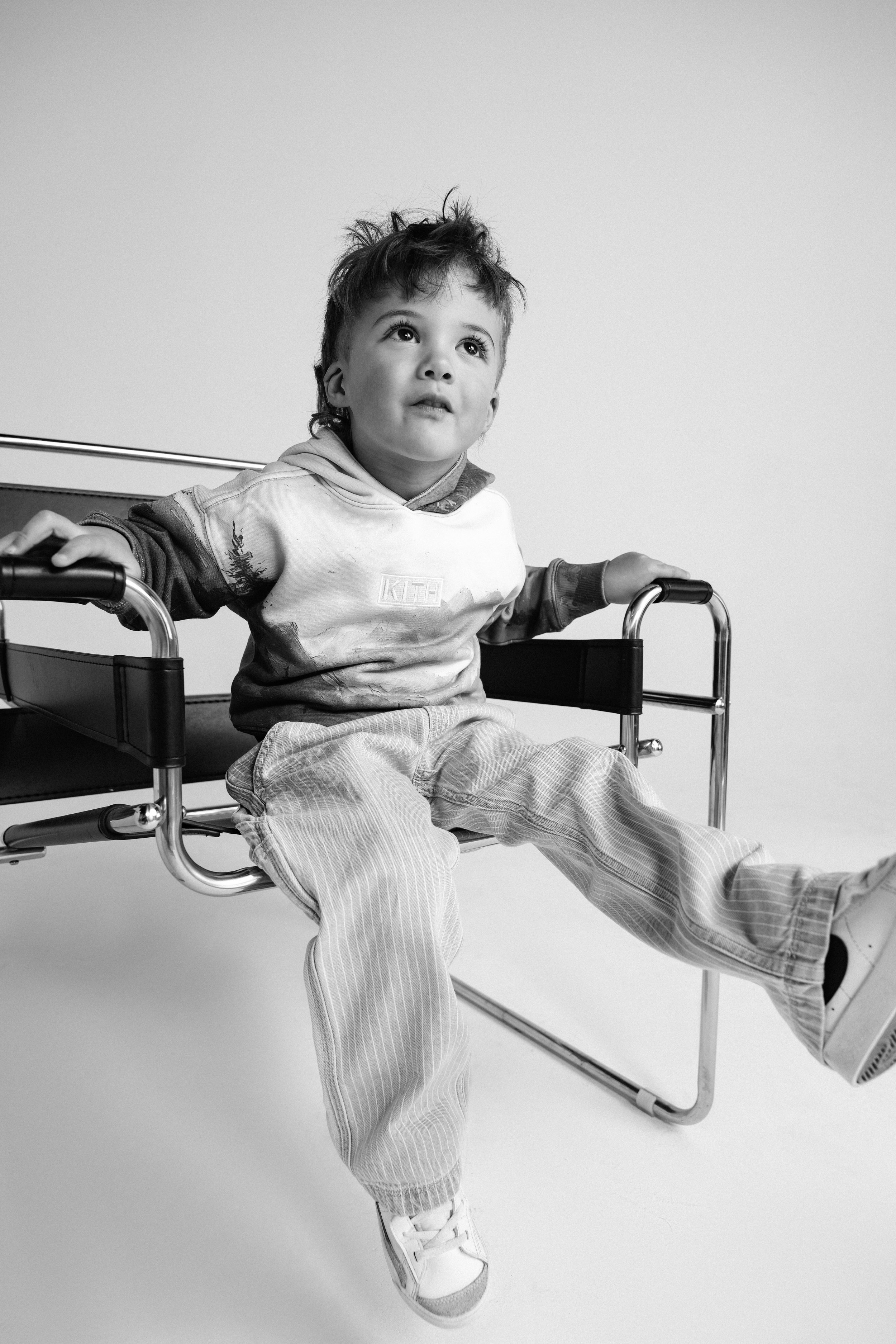 A young boy sitting in a wheelchair, looking upward with a thoughtful expression. Actor headshots for kids.