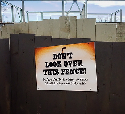 NO PEEKING?: A sign teases patrons of Silver Dollar City. Behind the fencing, the makings of a new ride are visible.