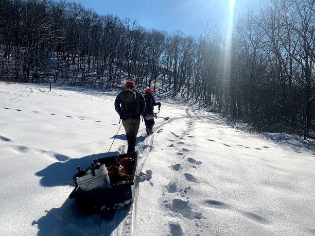  Crew hiking out to a remote site, gear loaded in a sled.  