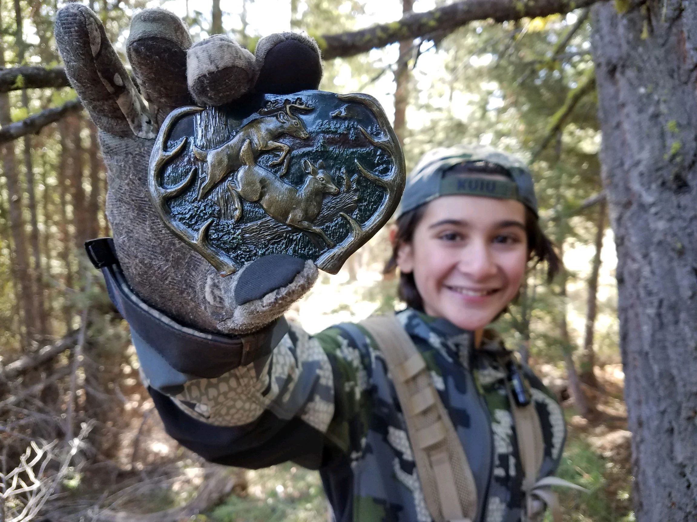 Young hunter in camouflage showing off a belt buckle imprinted with two leaping deer