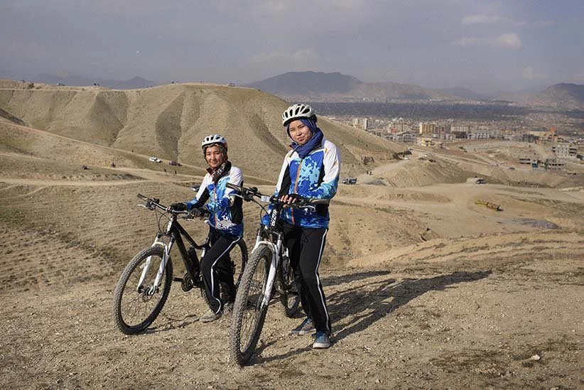 Teenage Afghan girls riding mountain bikes in the hills outside a city in Afghanistan