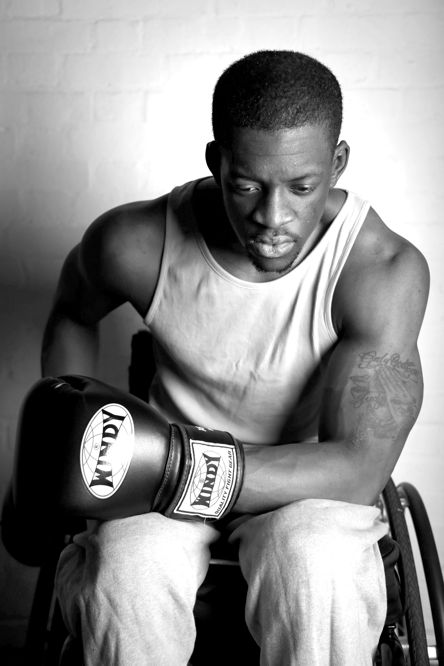 This is Marcus. He lost the use of his legs in a motorcycle accident 9 months prior to this photograph being taken. I met him in a boxing gym in Battersea. His mental strength astonished me. I wanted to visually champion the power of his mind in this portrait. I found the combination of a determined look with a pose celebrating his physical prowess not only did this, but it also quite literally overshadowed his chair. This is Marcus through and through - his chair is more a driving force than an obstruction.
