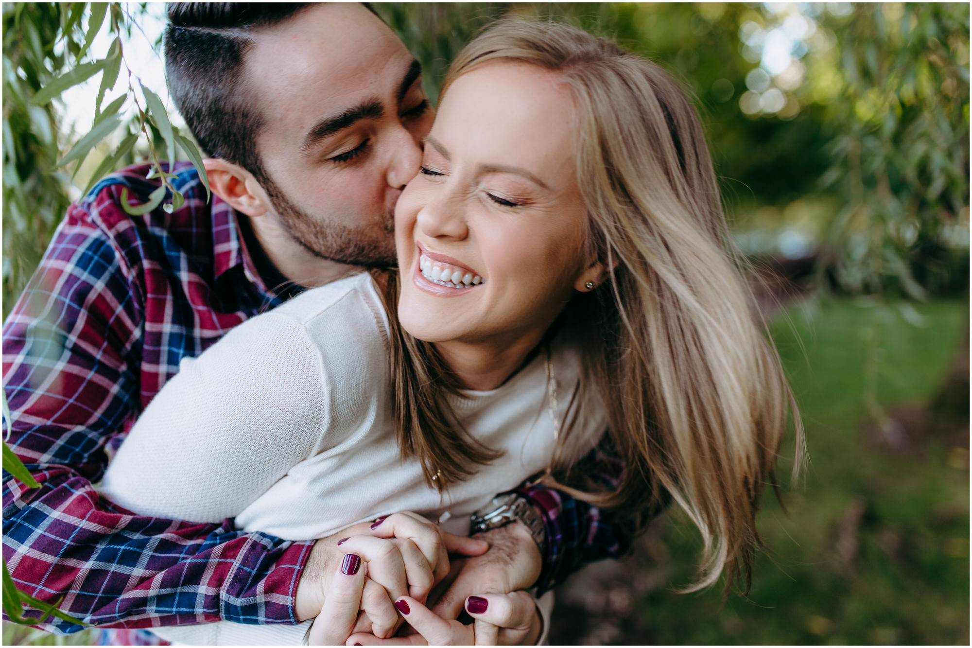 Beautiful engaged couple twirls around, man kisses his fiancee on the cheek and her hair blows in the wind - by New Hampshire wedding photographer Ashleigh Laureen Photography in Lowell, Massachusetts