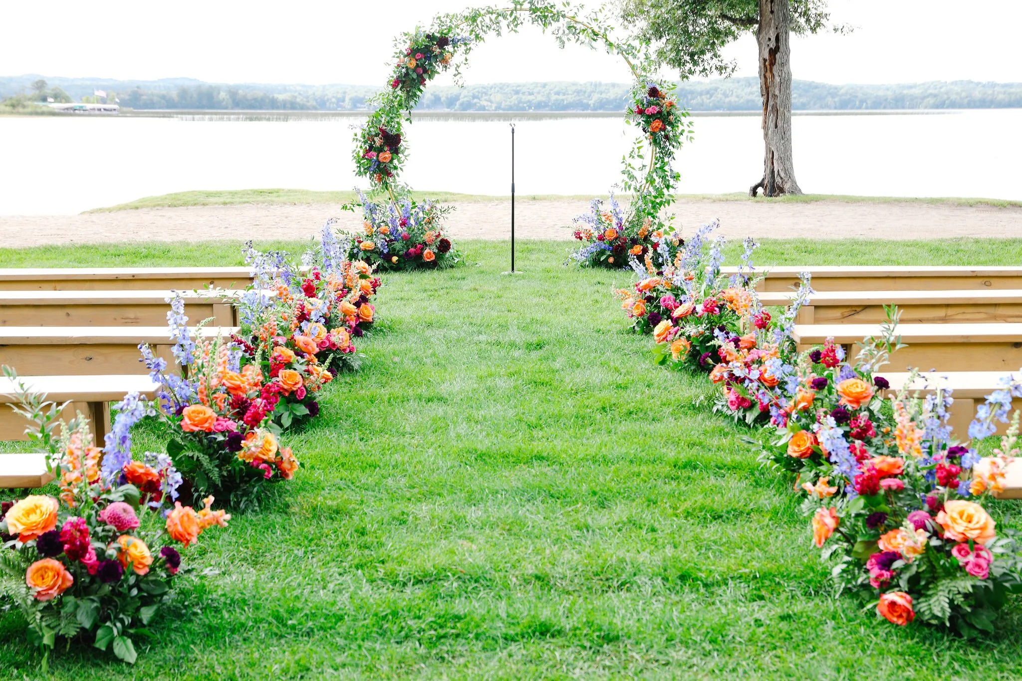 Flower arch and floral arrangements along a grassy aisle at an outdoor wedding venue near gull lake. Maddens wedding resort florist