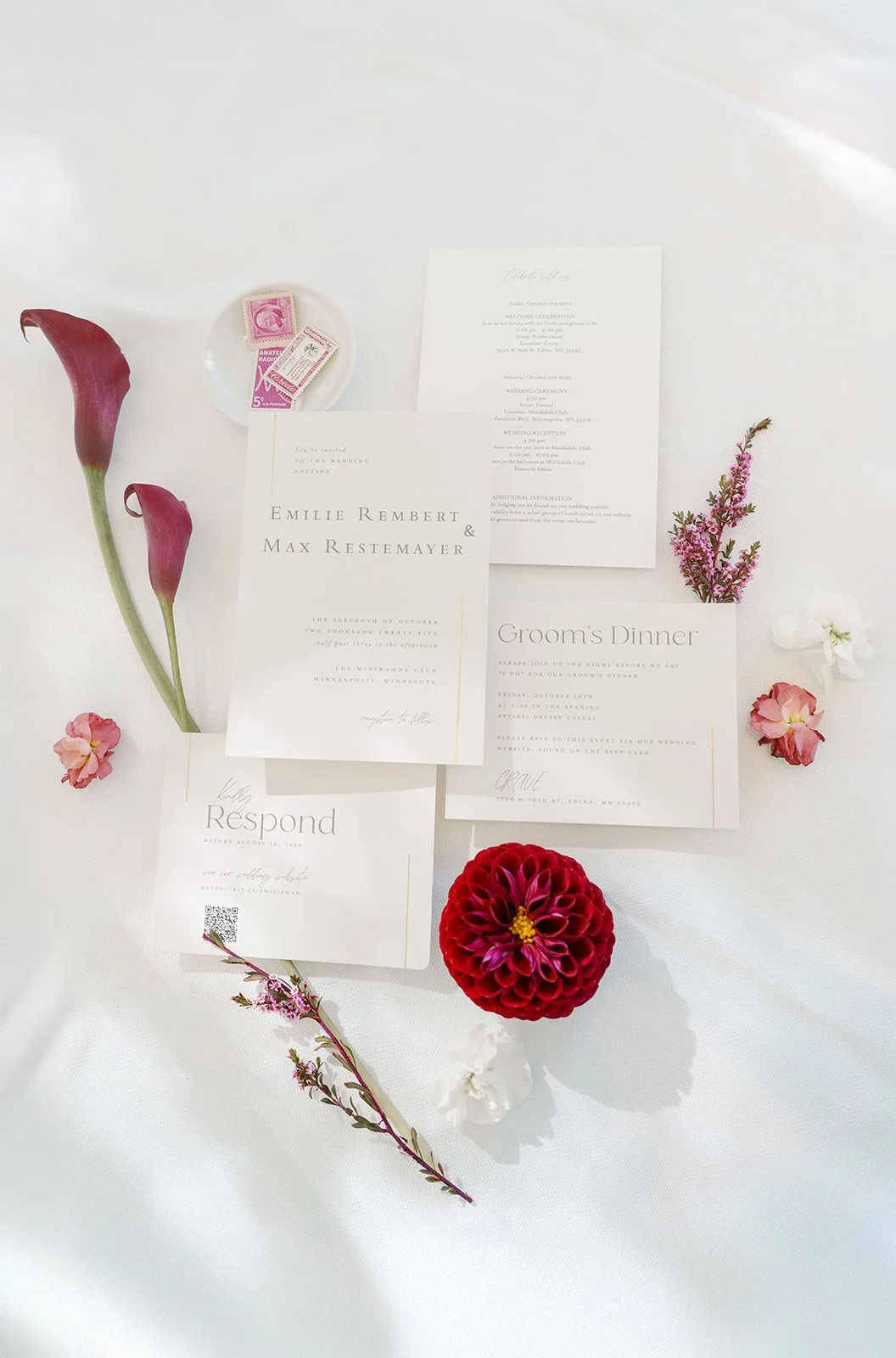 Wedding invitation suite with flowers and a small dish of vintage postage stamps, displayed on a white table. Minekahda club maroon mulberry florals wedding planning minneapolis wedding planner 