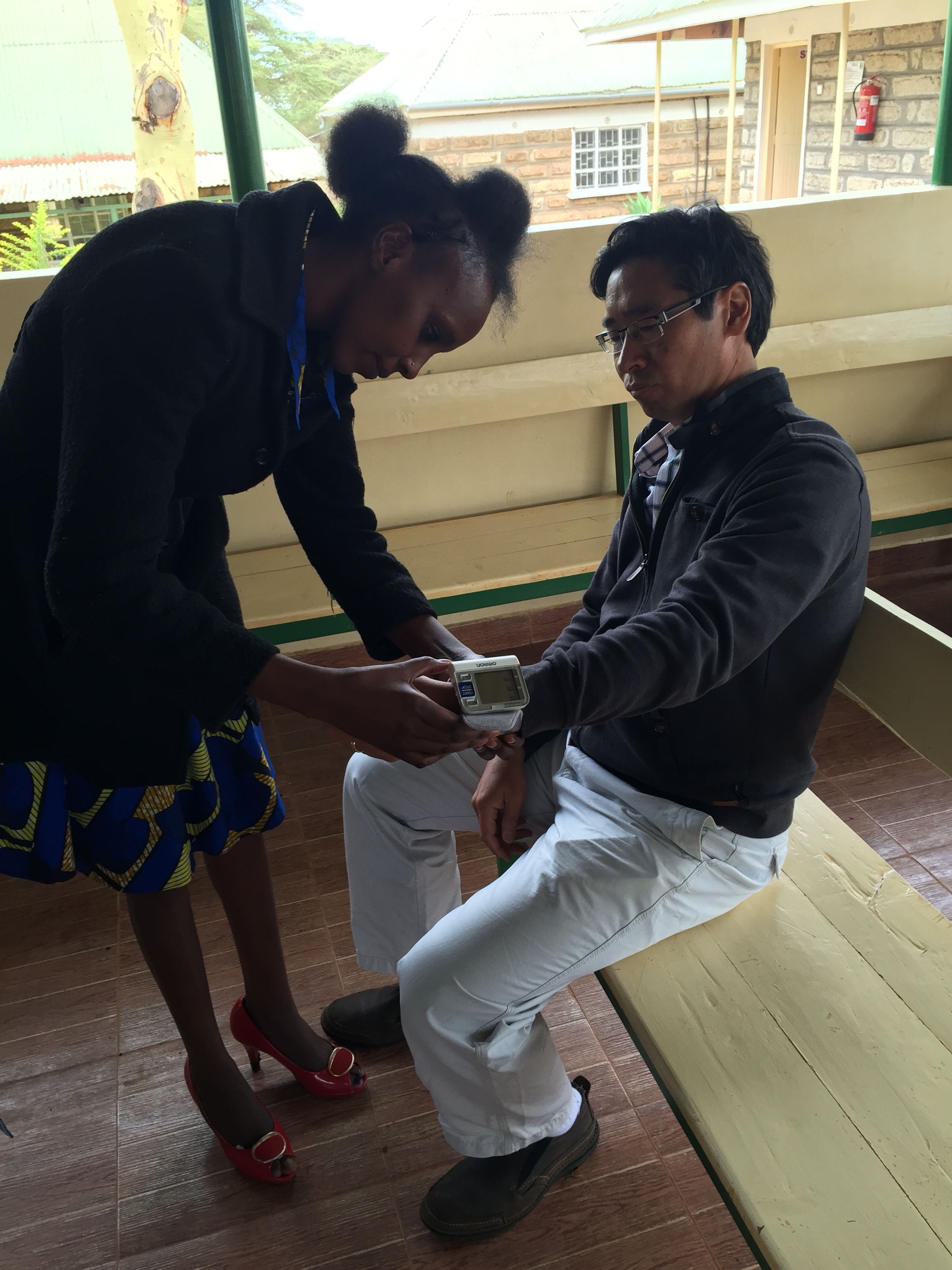 Emily, the community health worker, practising taking blood pressure on Dr. James Aw. 