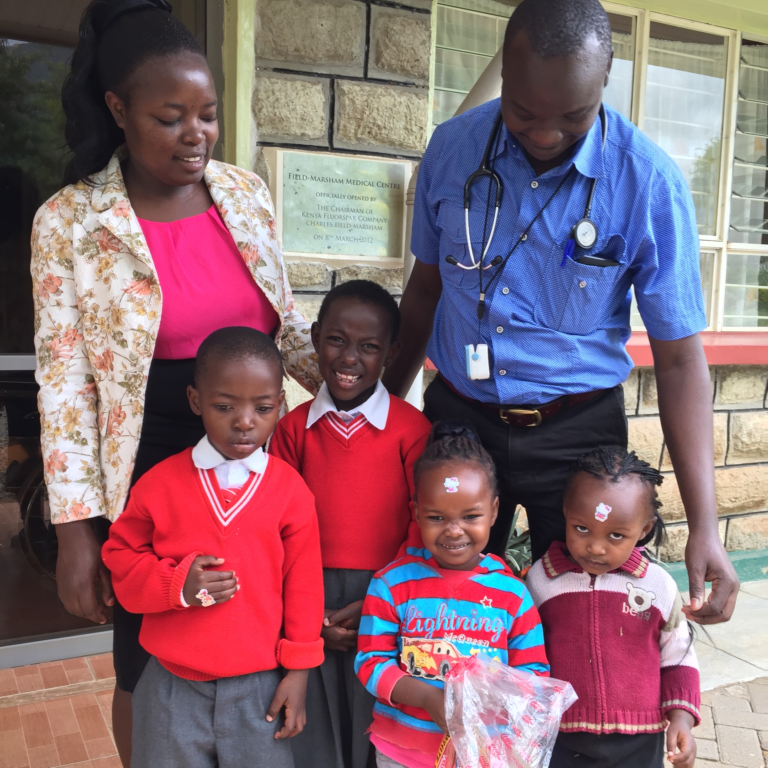 Julius with a happy family wearing stickers complements of Dr. Paul