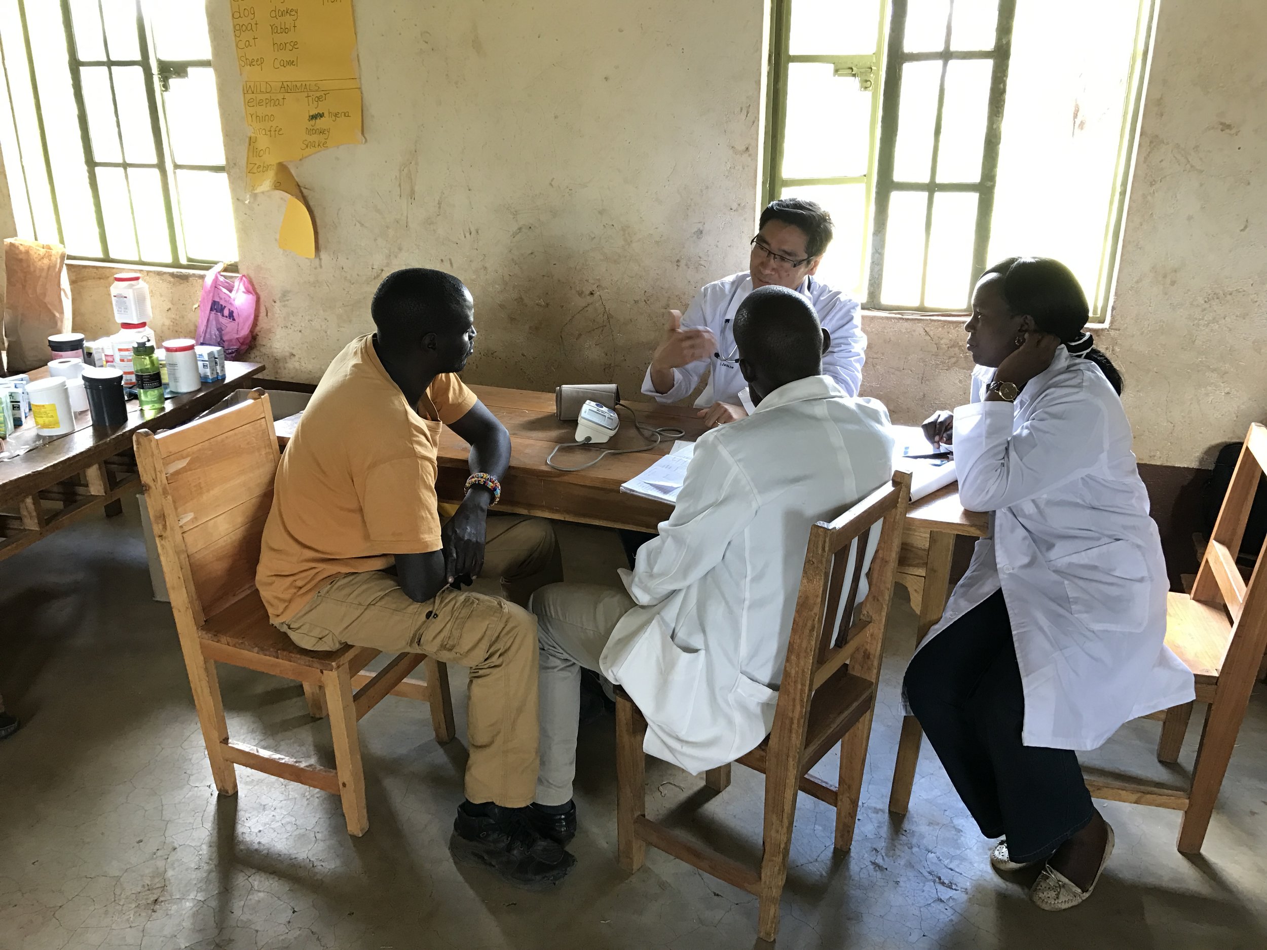  Dr. James working with two of the clinic staff, counselling them on chronic disease care while seeing a patient. 