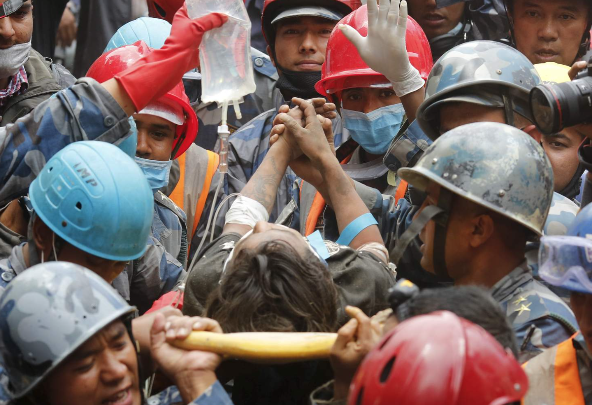 Pemba Tamang clasps the hands of his rescuers after being pulled from the rubble.