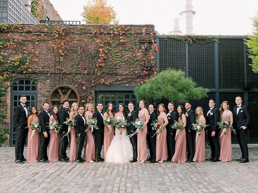 bridal party poses along brick wall at The Foundry | Tri-State area wedding venues photographed by Asher Gardner Photography
