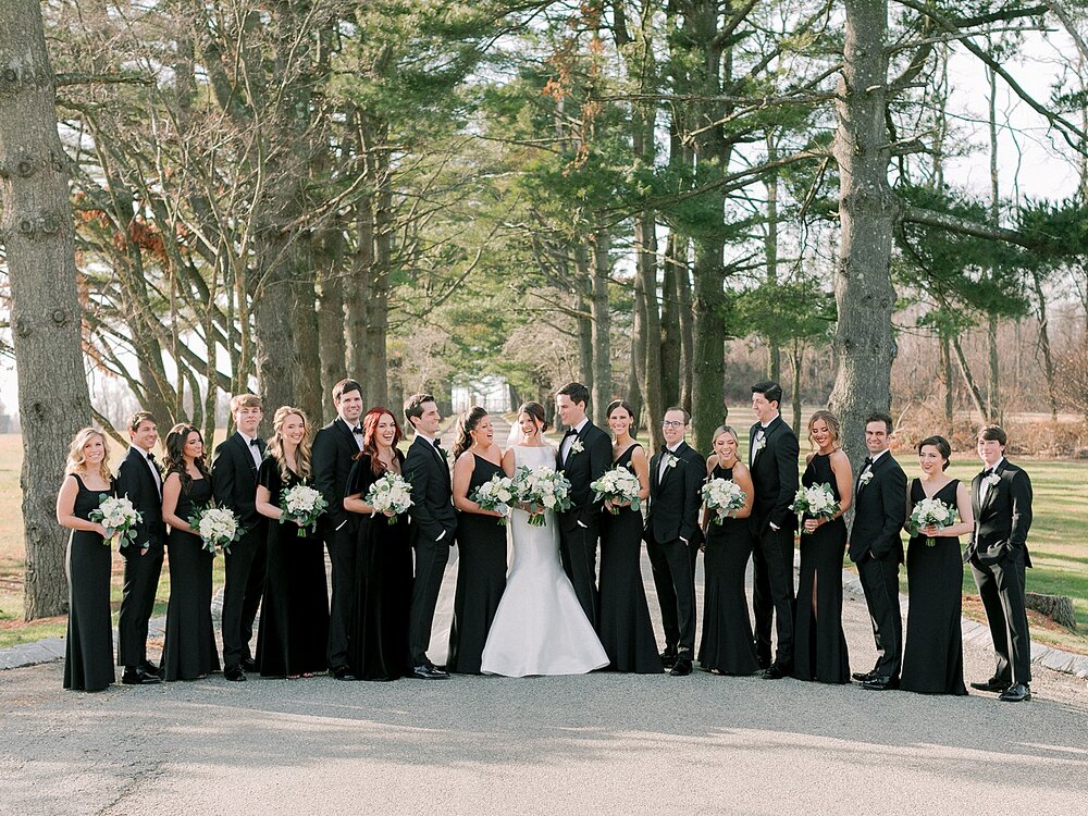 bride and groom pose with bridesmaids in black gowns at Ashford Estate | Tri-State area wedding venues photographed by Asher Gardner Photography