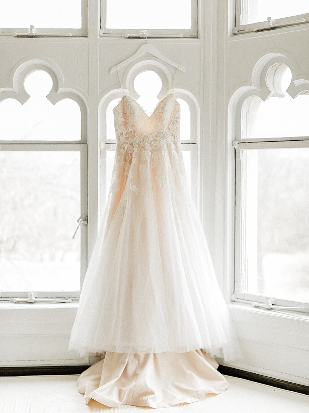 wedding dress hangs in detailed window at Hempstead House | Tri-State area wedding venues photographed by Asher Gardner Photography