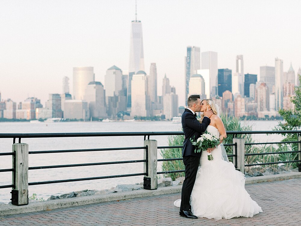 bride and groom pose in front of Manhattan skyline | Tri-State area wedding venues photographed by Asher Gardner Photography