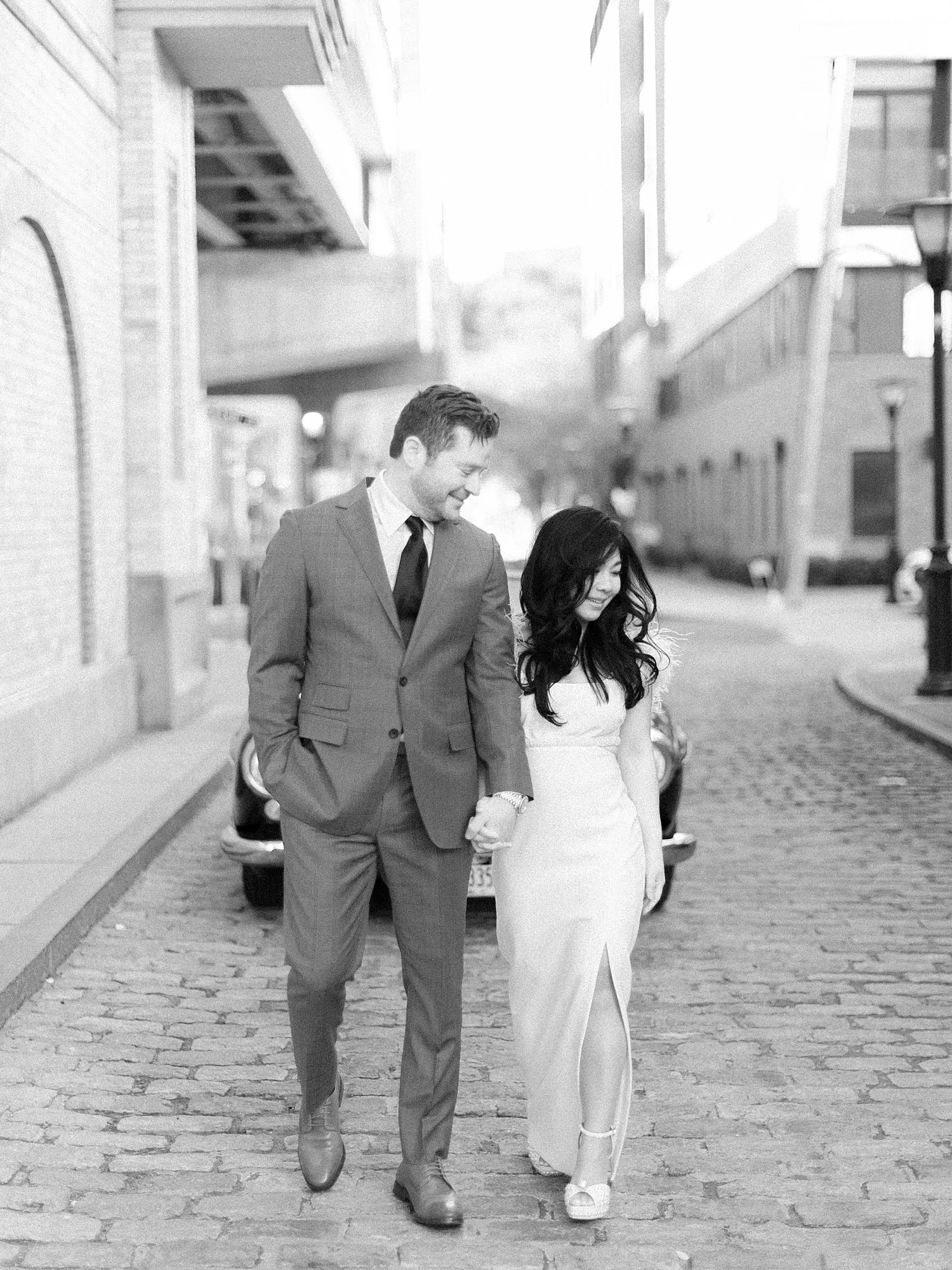 engaged couple holds hands walking through street of Hoboken NJ