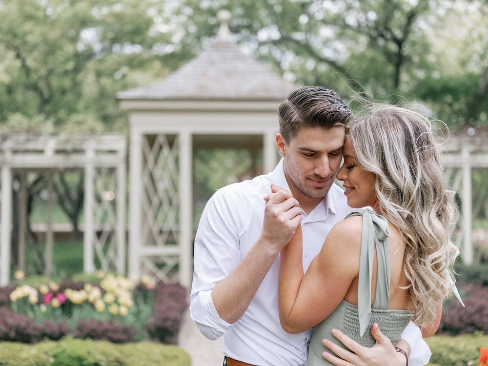 engaged couple hugs leaning together in front of gazebo in Philadelphia garden