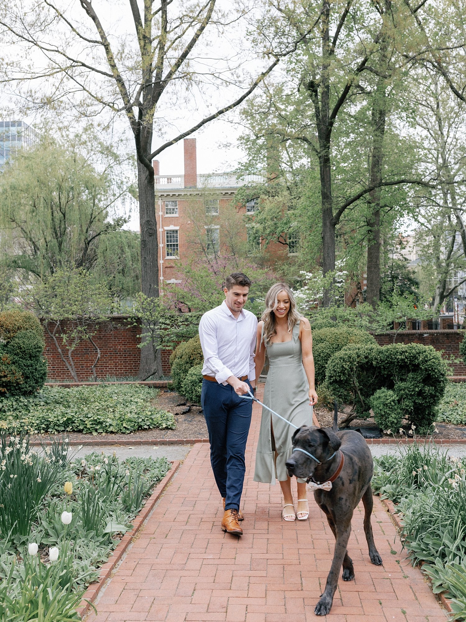 engaged couple walks through garden in Philadelphia with Great Dane