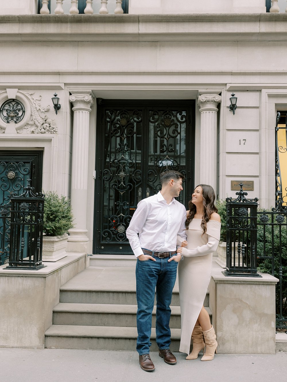 engaged couple leans against steps outside home on the Upper East Side of NYC