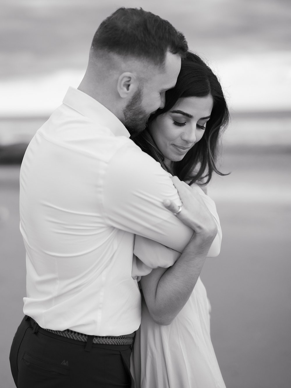 man hugs woman from behind on beach in Ocean City NJ