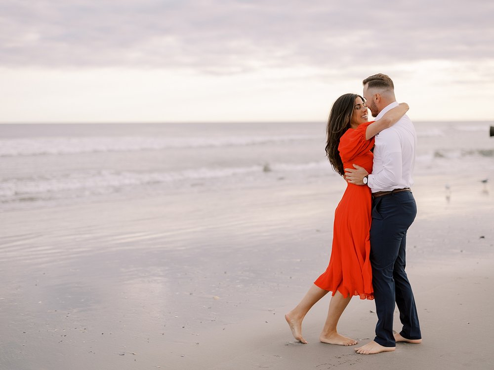 engaged couple hugs on beach at sunset in Ocean City NJ